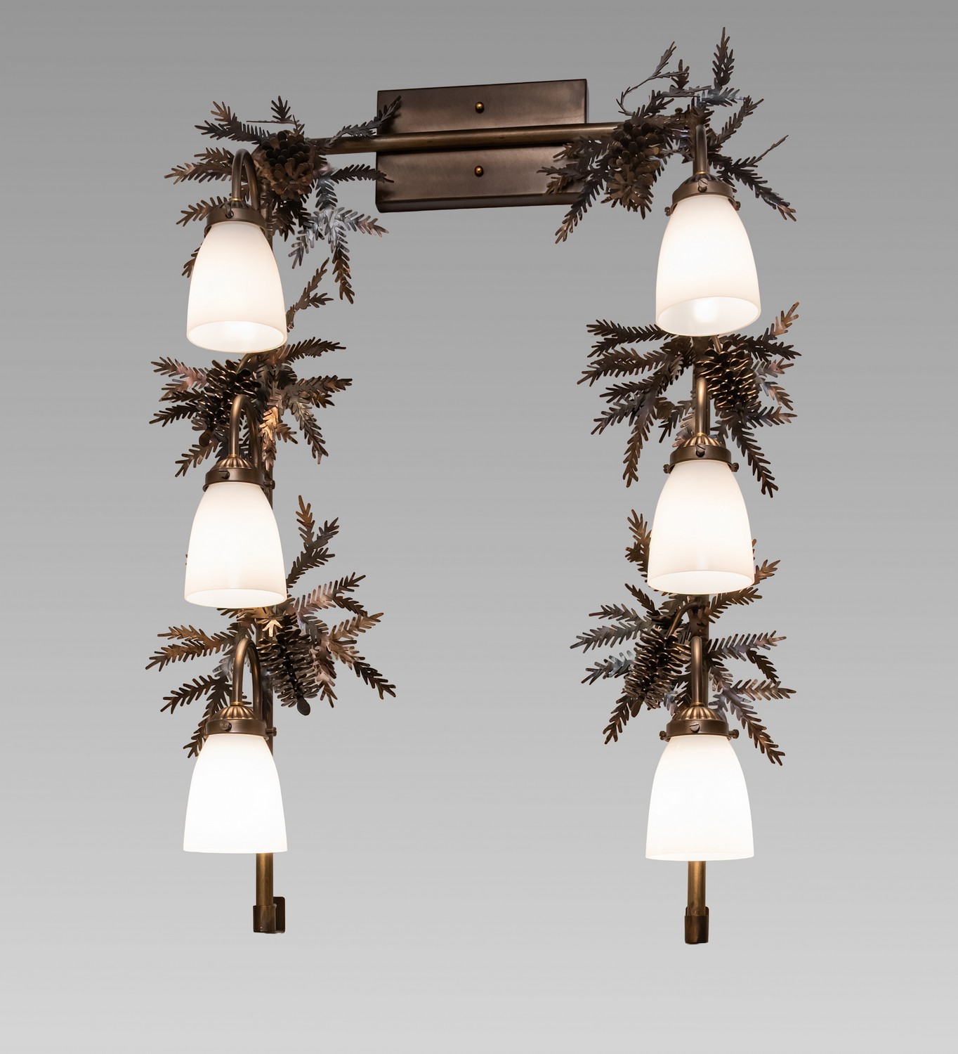 Invite the natural charm of the American woodlands into your camp, lodge, home, or business with this awe-inspiring vanity light. Six White Opal Glass shades are offered in this stunning Arts & Crafts design and feature Pine Branch-shaped metal arms with Pine-needle metal accents. This lovely, elaborate fixture features a warm Dark Burnished Antique Copper finish and is ideal for making a dramatic design statement in a fine bath or powder room. The Pine Branch 6 Light Vanity is included in our American-made, American-designed, handcrafted Rustic Lighting Collection and is manufactured in Yorkville, New York. UL and cUL listed for dry and damp locations. Upstate New York's adventurous playland, known as the Adirondack Mountains, with its many breathtaking forests, lakes, and rivers, is the spiritual birthplace of Meyda and inspires our rustic-themed collections. Collection: Pine Branch Finish: Dark Burnished Antique Copper Glass: White Opal Glass Width: 28.00" Height: 36.00" Length: 9.00" Weight: 14.00 lb Number of Bulbs: 6 Maximum Wattage: 60.00 W Bulb Type: A19 Bulb Base: E26 Material: Steel Country of Origin: USA Safety Rating: Damp